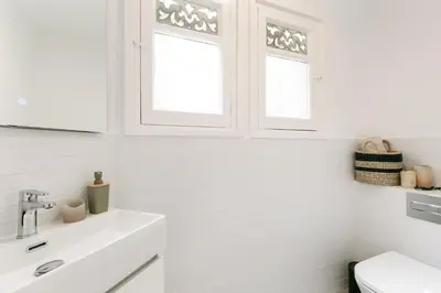 a white bathroom with a sink and two windows at Atrani - 3 bedroom in Eixample Dreta in Barcelona
