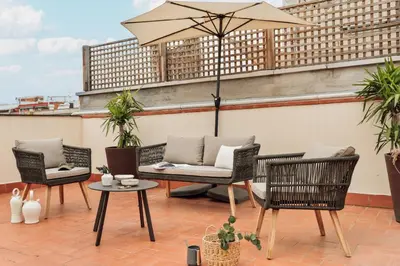 a patio with chairs and an umbrella on a roof at Cazalla - 2 bedrooms and office in Gràcia in Barcelona