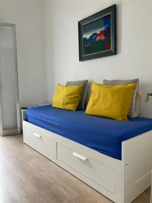 a bed with blue sheets and yellow pillows on it at Apartamento CAMP NOU in Hospitalet de Llobregat