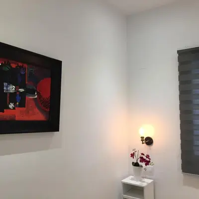 a white wall with a picture and a table with flowers at Apartamento CAMP NOU in Hospitalet de Llobregat