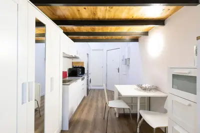 a kitchen with white cabinets and a wooden ceiling at Homenfun Barcelona Ciutat Vella in Barcelona