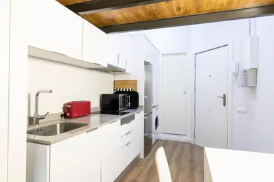 a kitchen with white cabinets and a sink at Homenfun Barcelona Ciutat Vella in Barcelona
