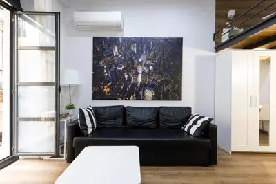 a living room with a black couch and a painting at Homenfun Barcelona Ciutat Vella in Barcelona