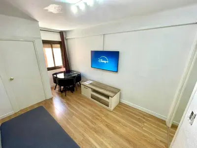 a living room with a table and a tv on a wall at Gran apartamento nuevo de 3 Hab, a 1 minuto del metro HBB in Hospitalet de Llobregat