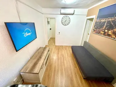 a room with a couch and a clock on the wall at Gran apartamento nuevo de 3 Hab, a 1 minuto del metro HBB in Hospitalet de Llobregat
