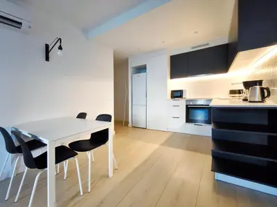 a kitchen with a white table and black chairs at Apartamento céntrico, moderno, Terrassa Rambla in Terrassa