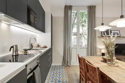 a kitchen with black cabinets and a wooden table at Sazos - 2 bedrooms in Sant Antoni in Barcelona