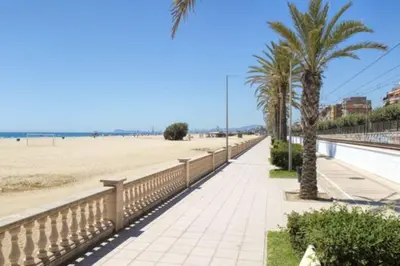 a sidewalk next to a beach with palm trees at New penthouse duplex by the sea in Masnou