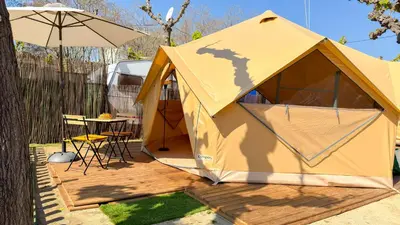 a tent with a table and a chair on a deck at Camping Costa Dorada in Canet de Mar