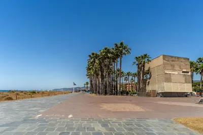 an empty street with palm trees and a building at Canela Homes COSTA PALMERES in Castelldefels