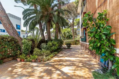 a walkway in front of a building with palm trees at Canela Homes COSTA PALMERES in Castelldefels