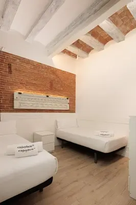 a room with two beds and a brick wall at Colon Deluxe con Piscina cerca del Mar in Barcelona
