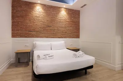 a bed in a room with a brick wall at Colon Deluxe con Piscina cerca del Mar in Barcelona