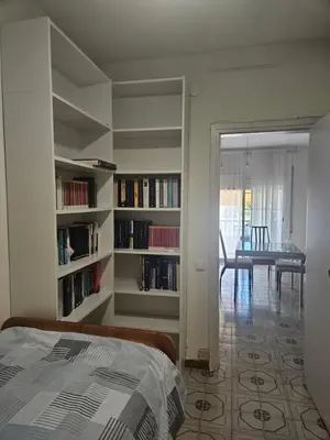 a bedroom with bookshelves and a dining room with a table at Apartamento Luminoso en el Centro de Sitges in Sitges