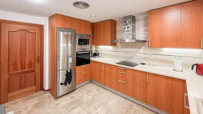 a kitchen with wooden cabinets and a stainless steel refrigerator at Villa Marina in Sitges