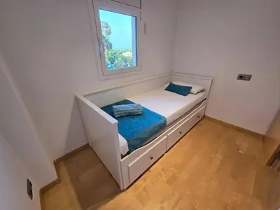 a small bed in a room with a window at Aquamarina Apt | Seaviews | 1' beach | Family in San Pol de Mar
