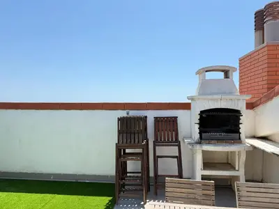 two chairs and an outdoor oven on a roof at Dúplex con encanto en Castelldefels in Castelldefels