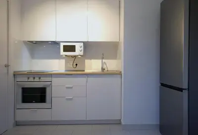 a kitchen with white cabinets and a microwave at Winahost Barcelona Sants in Barcelona
