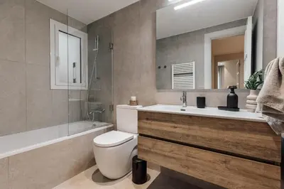 a bedroom with a bed and a dresser and a bathroom at Kadikoy - 4 bedrooms and terrace in Sant Gervasi in Barcelona