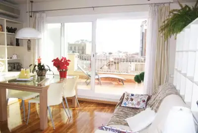 a living room with a white couch and a table and a window at Attic with terrace Barcelona center in Barcelona