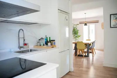 a white kitchen with a sink and a table at Apartamento - Recinto Modernista in Barcelona