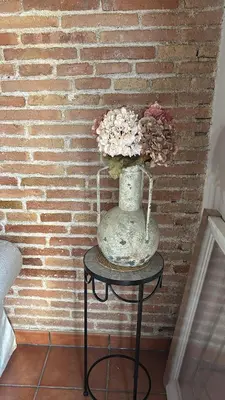 a vase with flowers on a table in front of a brick wall at Balcón, WiFi y aire acondicionado en Plaza Cataluña in Barcelona