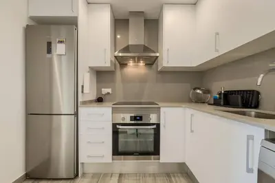 a kitchen with white cabinets and a stainless steel refrigerator at Comfort, Style & Value near Barceloneta Beaches in Barcelona