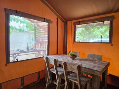 a dining room with a table and a bunk bed at Camping Costa Dorada Tienda Lua in Canet de Mar