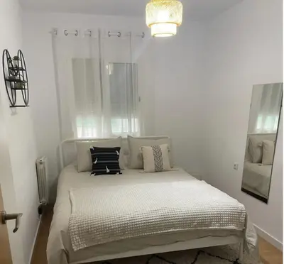 a white bedroom with a bed with pillows on it at Alojamiento espacioso ideal para visitas en grupo in Terrassa