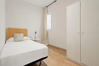 a bedroom with a white bed and a large closet at Flateli Espronceda 32 in Barcelona