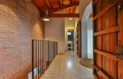 a hallway with a brick wall and a wooden door at Sun & Sand Sanctuary - 2km to beach and 20km BCN! in Castelldefels