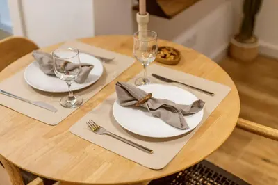 a wooden table with white plates and silverware on it at Lodging Apartments Almirall Beach B1 in Barcelona