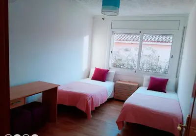 a small room with two beds and a window at La Casa de Vacaciones in Terrassa