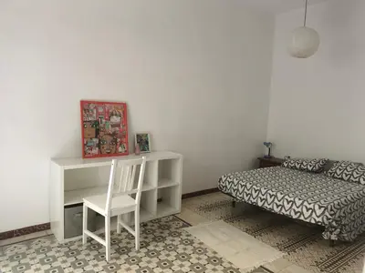 a bedroom with a bed and a desk and a chair at Habitación grande con balcón y mucha luz in Barcelona
