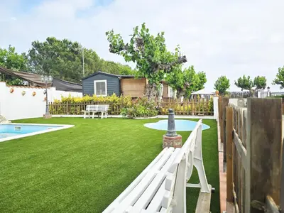 a backyard with a white fence and a yard with a pool at Costa Dorada Tiny Amaia in Canet de Mar