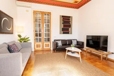 a living room with a couch and a tv at Apartamento de Lujo 7 Hab con balcón en Gran Vía -Grupos hasta 14 - 8min a pie Passeig Gràcia in Barcelona
