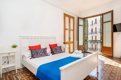 a bedroom with a large white bed with red and blue pillows at Apartamento de Lujo 7 Hab con balcón en Gran Vía -Grupos hasta 14 - 8min a pie Passeig Gràcia in Barcelona