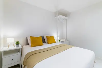 a white bedroom with a bed with yellow pillows at Furnished & Fully Equipped 2BR near the beach in Barcelona