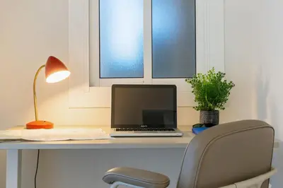 a desk with a laptop and a lamp and a chair at Furnished & Fully Equipped 2BR near the beach in Barcelona
