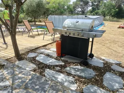 a barbecue grill sitting on a patio next to a tree at Large house surrounded by nature in Vilanova de la Roca