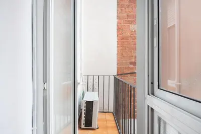 an open door to a balcony with a trash can at Charm and Comfort in the Heart of Sant Antoni, Barcelona in Barcelona