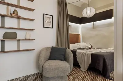 a room with white cabinets and a chair in front of a window at Tiqui - 1 bedroom and balcony in Vila de Gràcia in Barcelona
