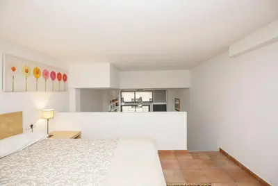 a white bedroom with a bed and a kitchen at Urban Gracia in Barcelona