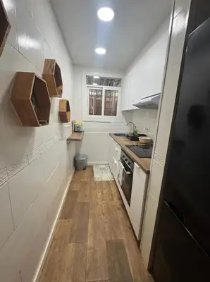 a small kitchen with white walls and wooden floors at Hermoso Apartamento cerca a Barcelona in Sant Adria de Besos