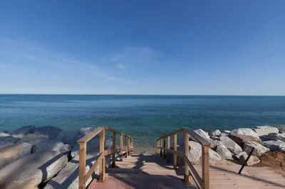 a wooden walkway leading to the ocean with rocks at Traumhäuschen am Meer für 2, Barcelona in Vilassar de Mar