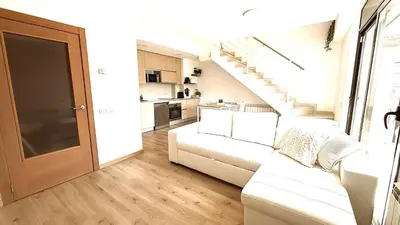 a living room with a white couch and a staircase at Dúplex zona olimpica by Prestigi in Terrassa