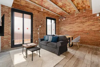 a living room with a couch and a brick wall at Sants Apartment in Barcelona