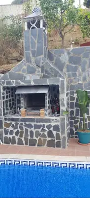a stone fireplace sitting next to a swimming pool at casa vacacional con piscina privada in Sant Cebrià de Vallalta