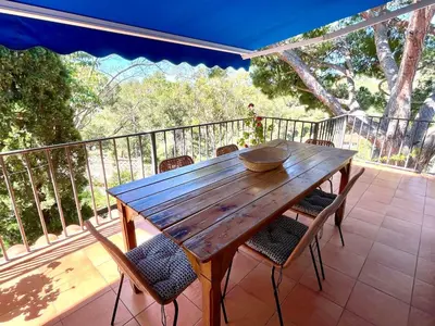 a wooden table and chairs on a balcony at Casa familiar con piscina cerca del mar y montaña in San Pol de Mar