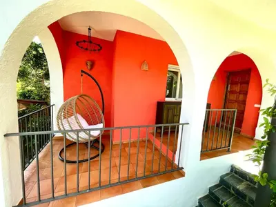 a room with an orange wall and a chair on a balcony at Casa familiar con piscina cerca del mar y montaña in San Pol de Mar